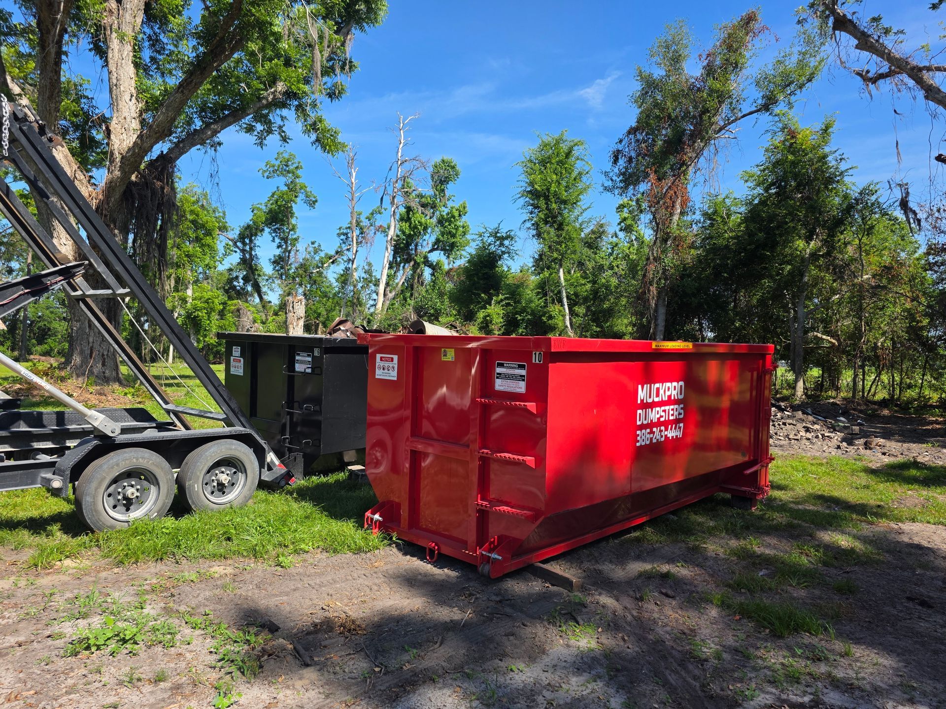 A large black dumpster is sitting in the middle of a field in McAlpin, Florida