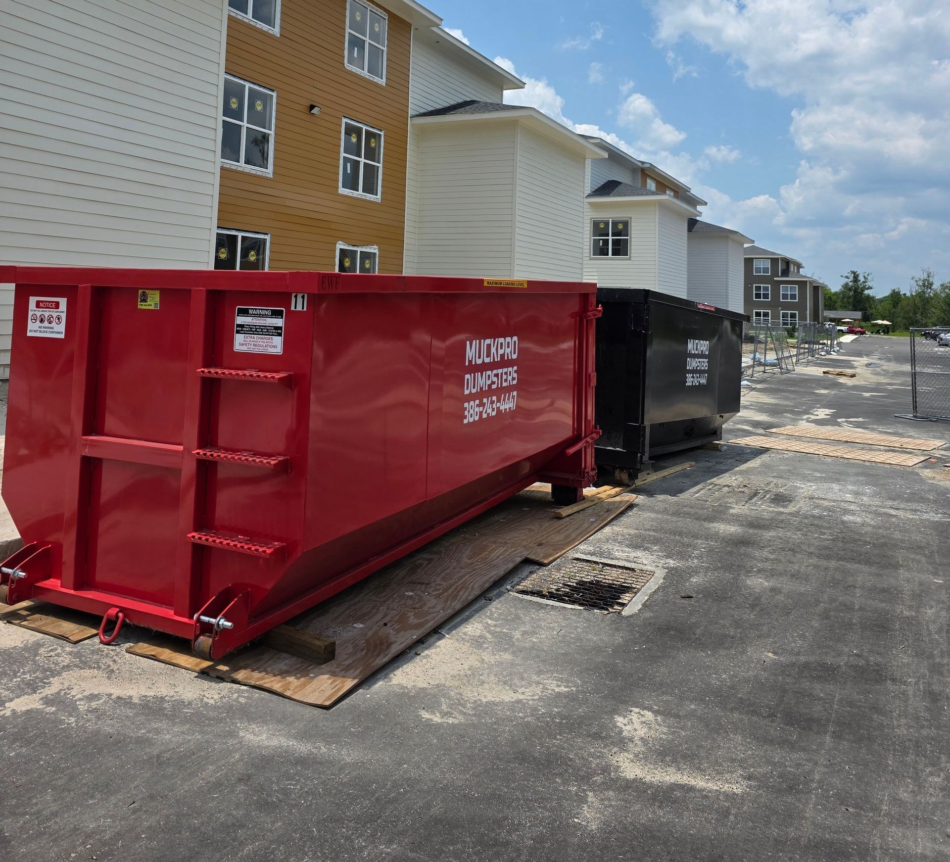 A red muckpro dumpster sits in front of a house in Live Oak, Florida
