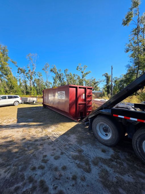 A large black dumpster is sitting in the middle of a field in McAlpin, Florida