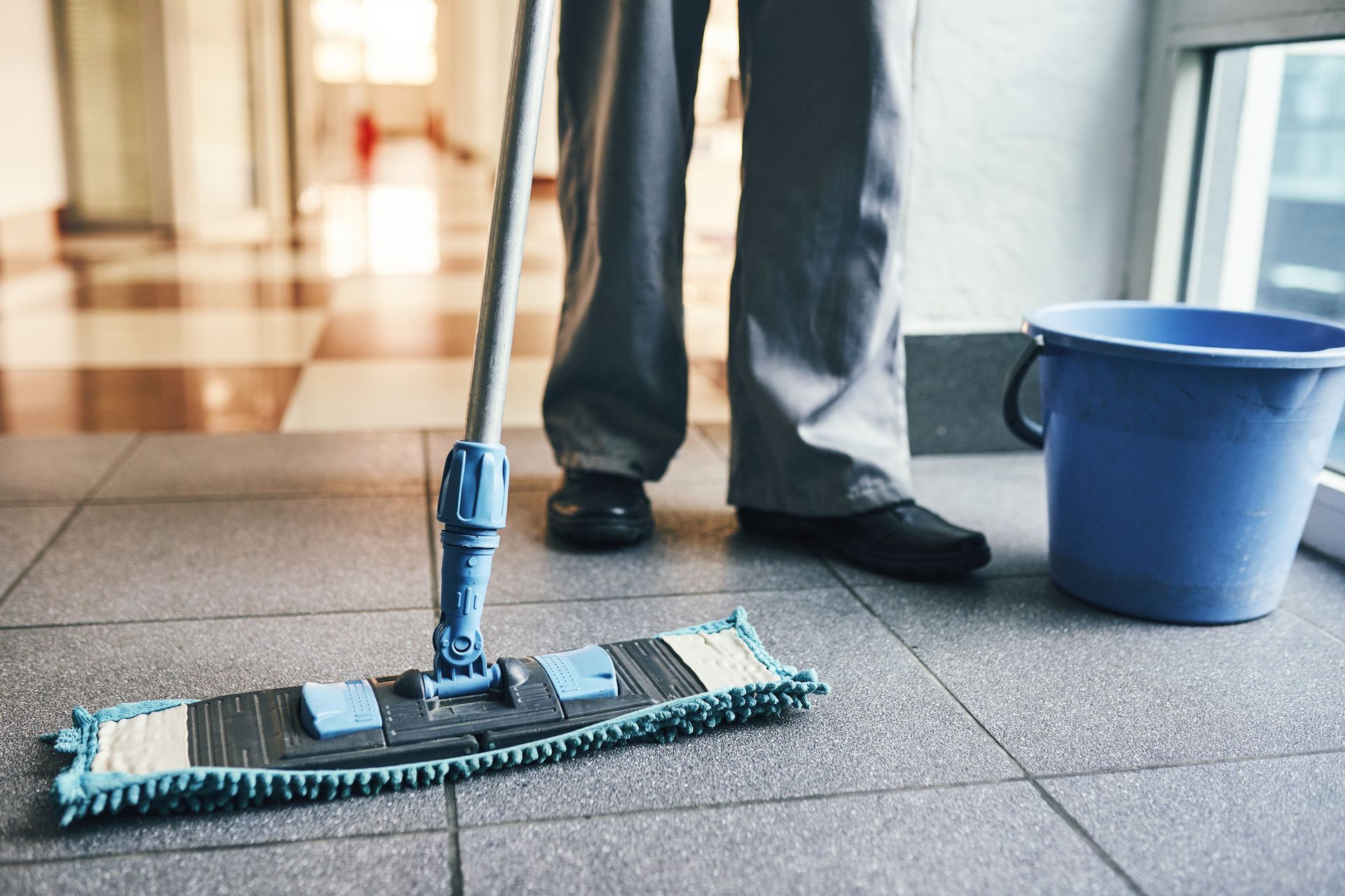 Office cleaning service with mop and bucket on tiled floor.