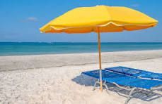 A yellow umbrella is sitting on a beach next to a blue chair.