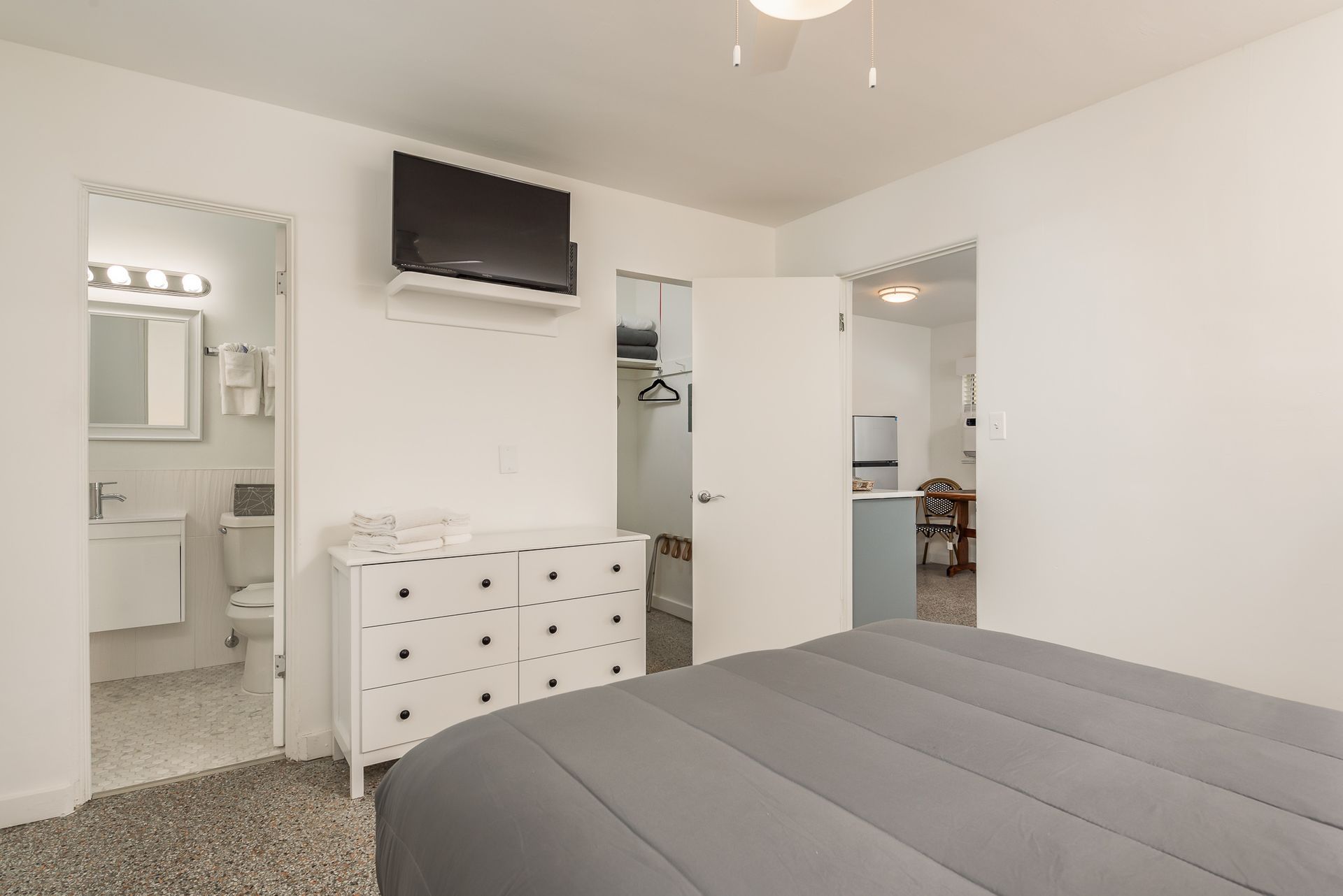 A bedroom with a bed , dresser , television and bathroom