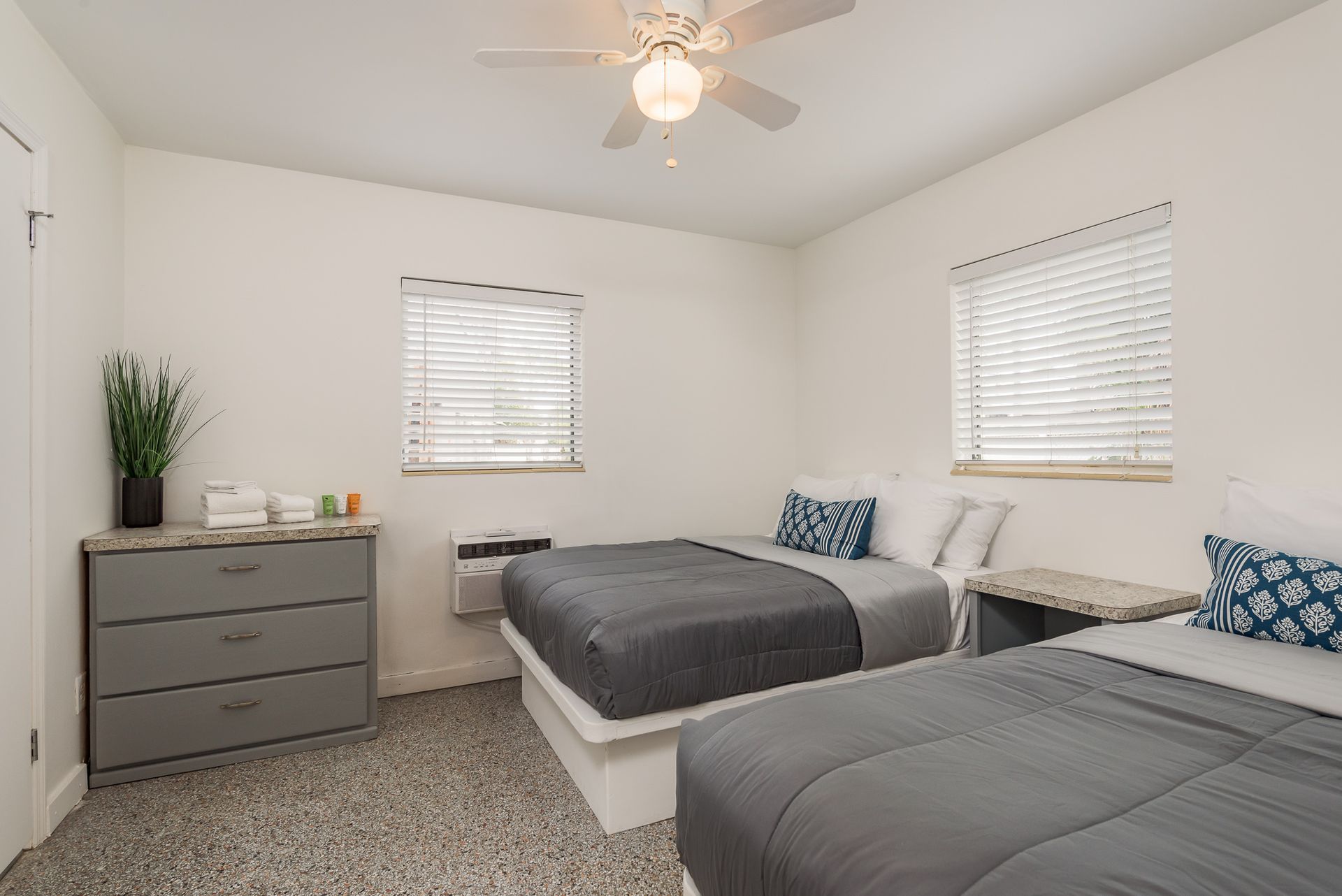 A bedroom with two beds and a ceiling fan