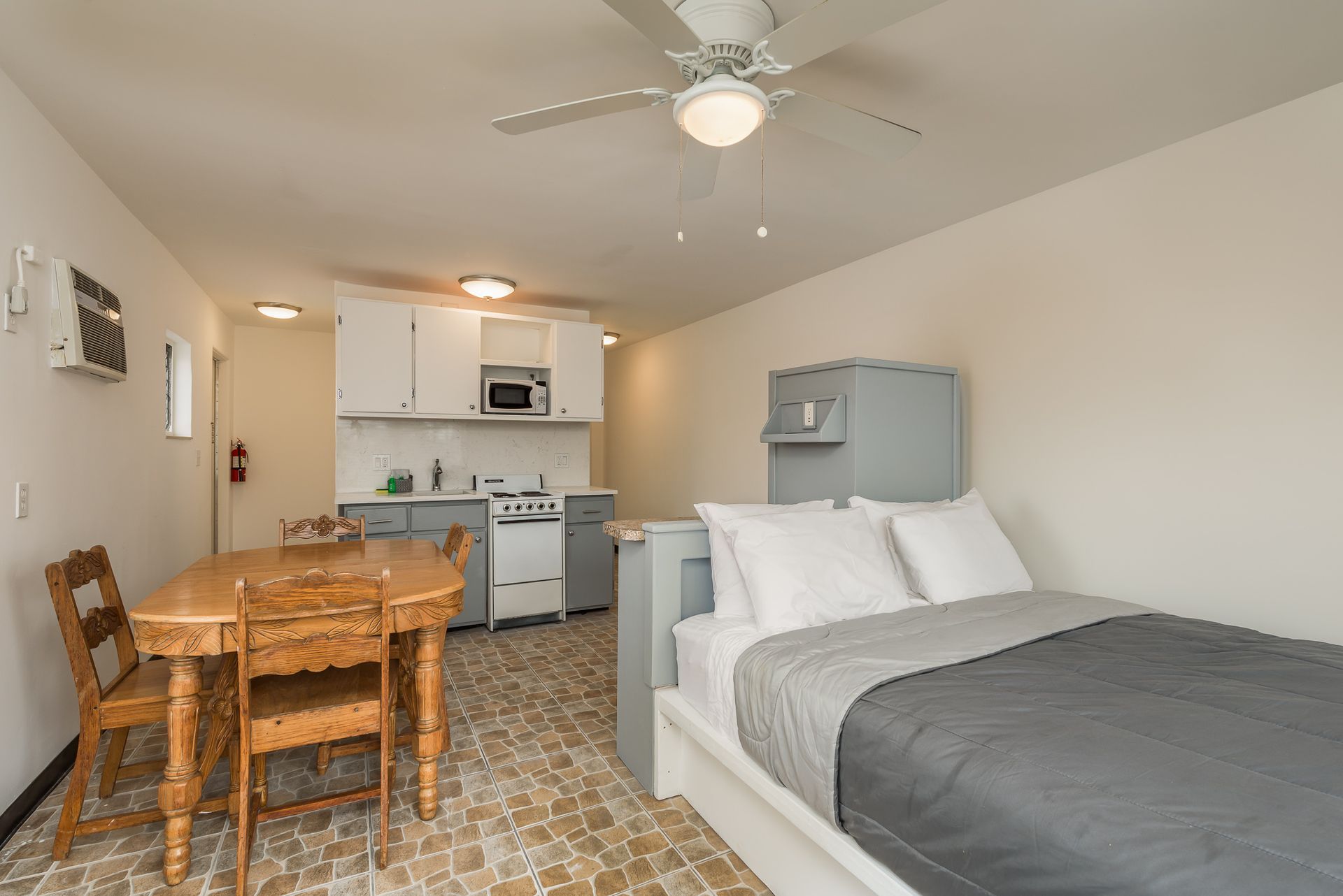 A bedroom with a bed , table and chairs and a ceiling fan.