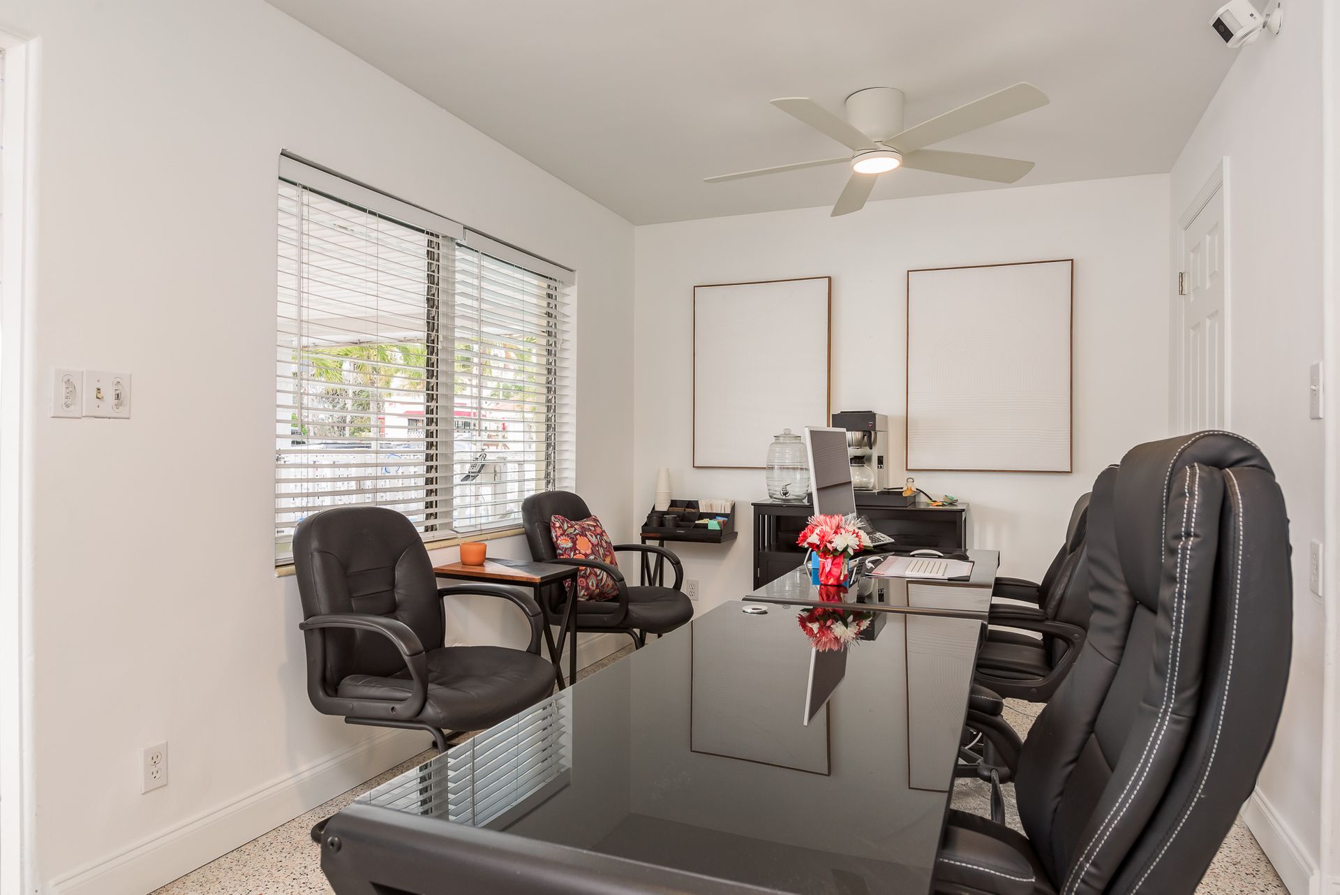 A conference room with a long table and chairs and a ceiling fan.