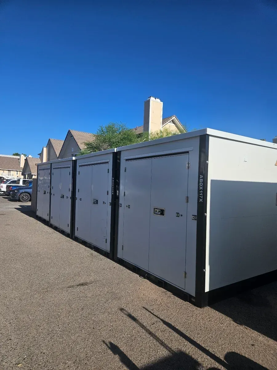 Row of large white storage containers beside a street under a clear blue sky