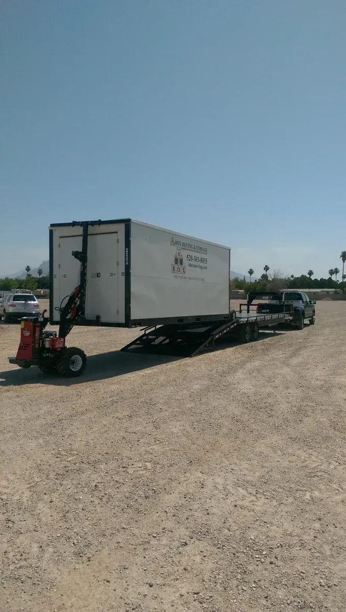 White trailer on flatbed in gravel lot under clear blue sky