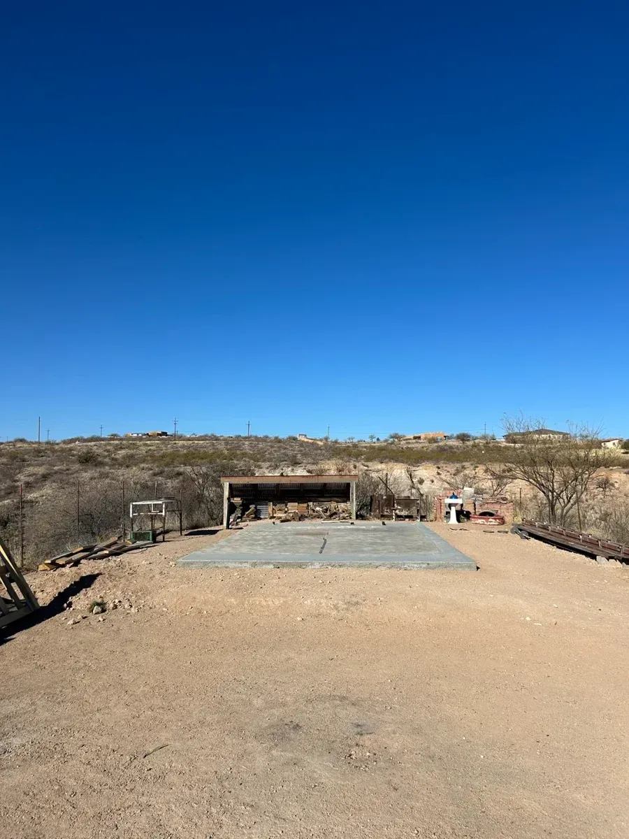 Desert landscape with a concrete platform and low stone structure under a clear blue sky