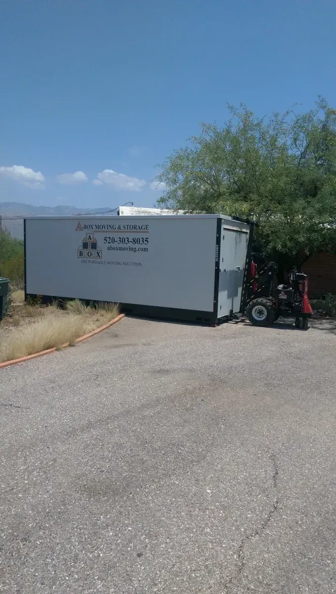 White cargo trailer on a roadside with a person on a red mobility scooter beside it under a blue sky