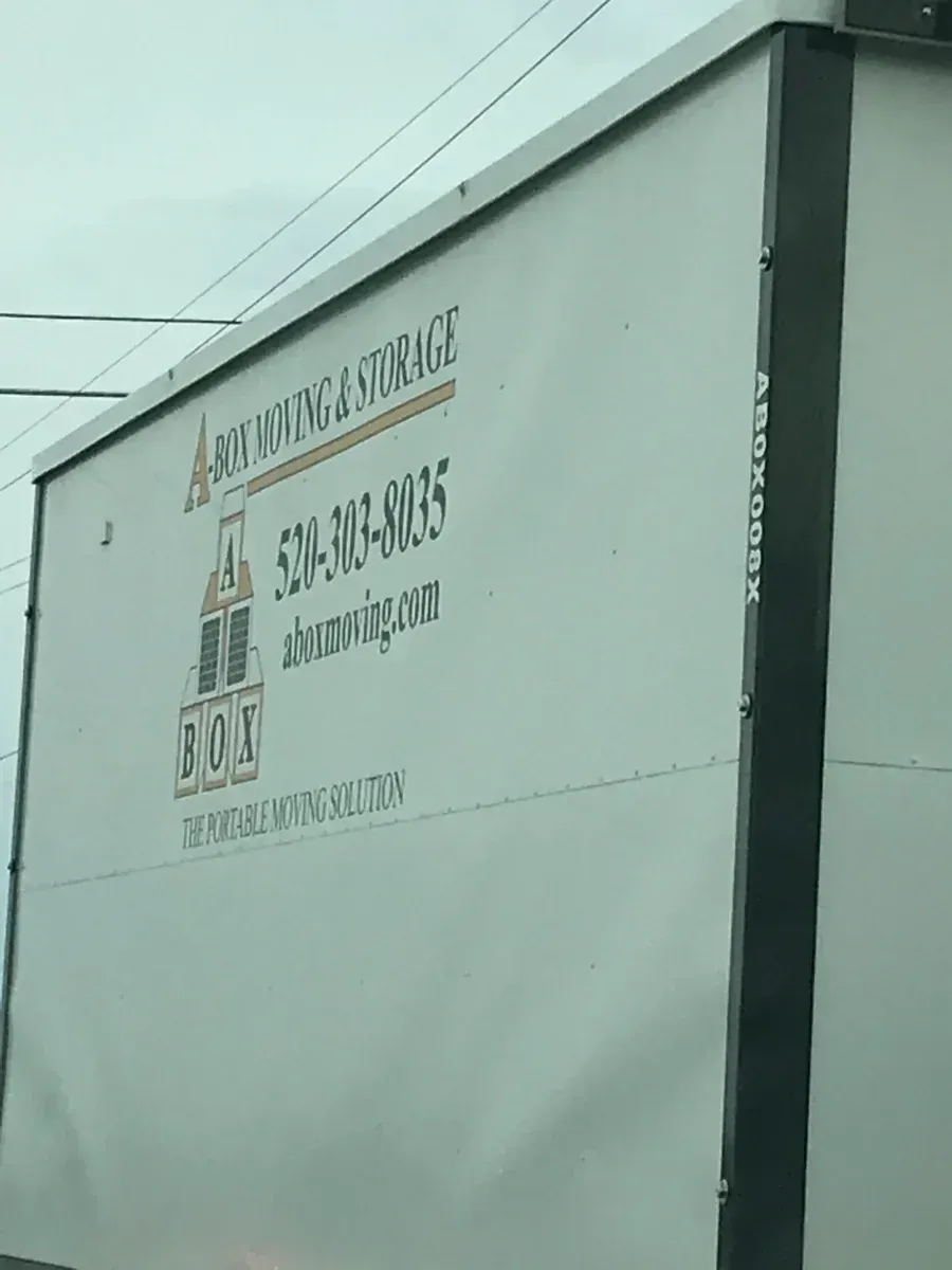White building wall with a phone number and sign near a rooftop cable line
