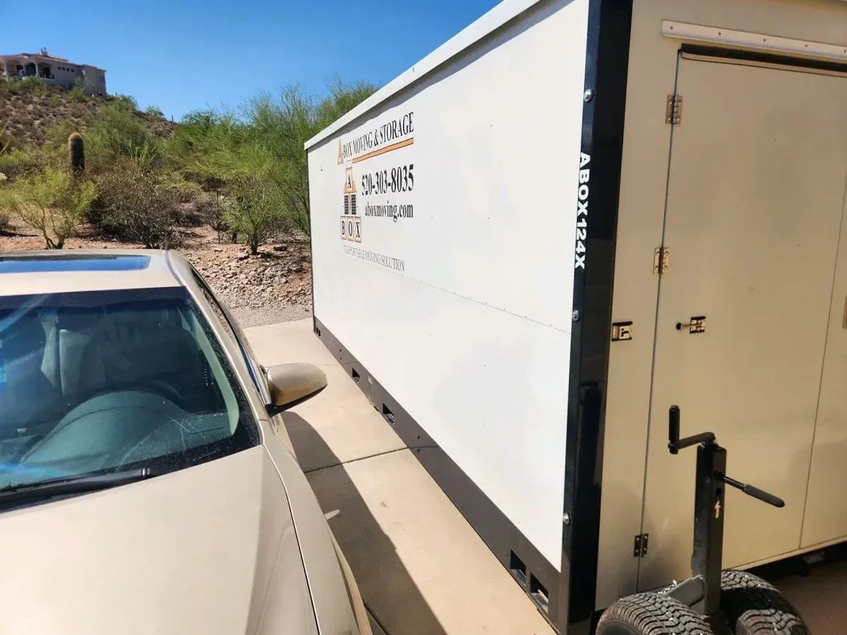 White box truck parked beside a beige car on a sunny desert road