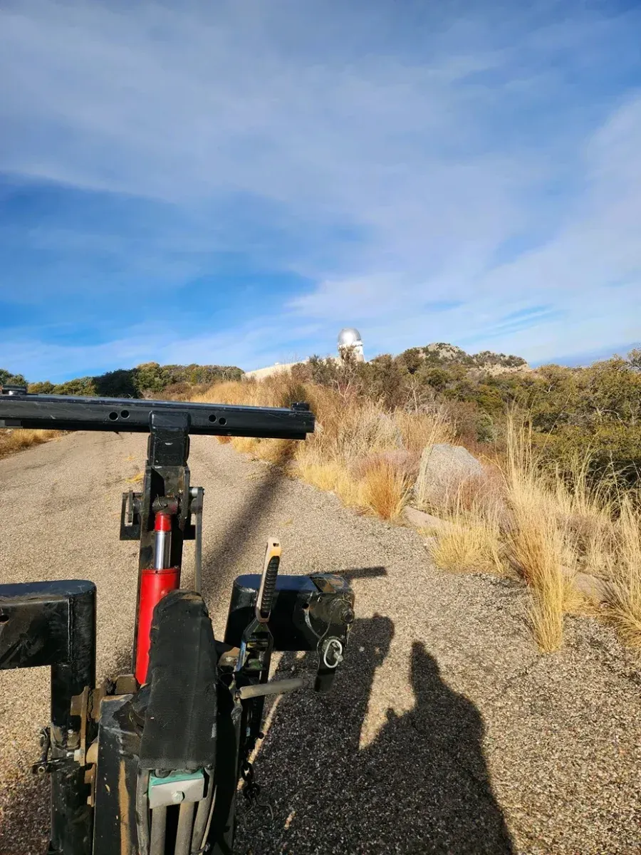 Bicycle handlebar view on a gravel trail in a dry, grassy landscape under a blue sky