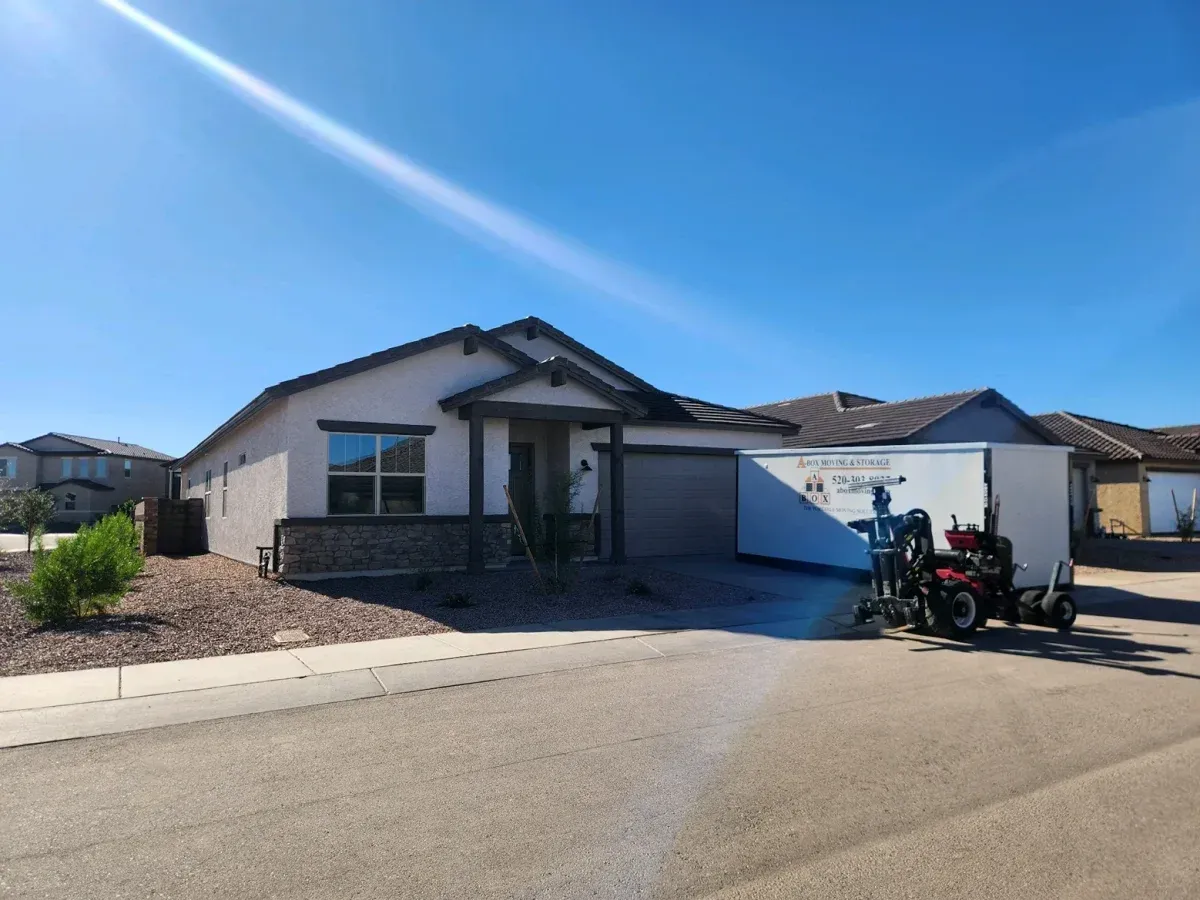 Suburban house with a two-car garage and parked motorcycle in the driveway under a bright blue sky