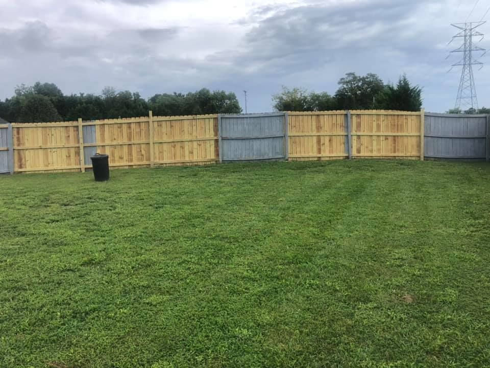 A wooden fence surrounds a lush green field.