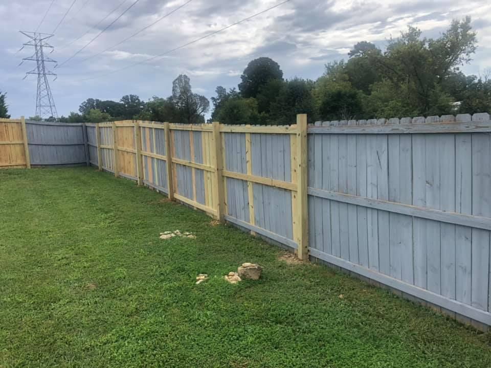 A wooden fence is sitting in the middle of a lush green field.