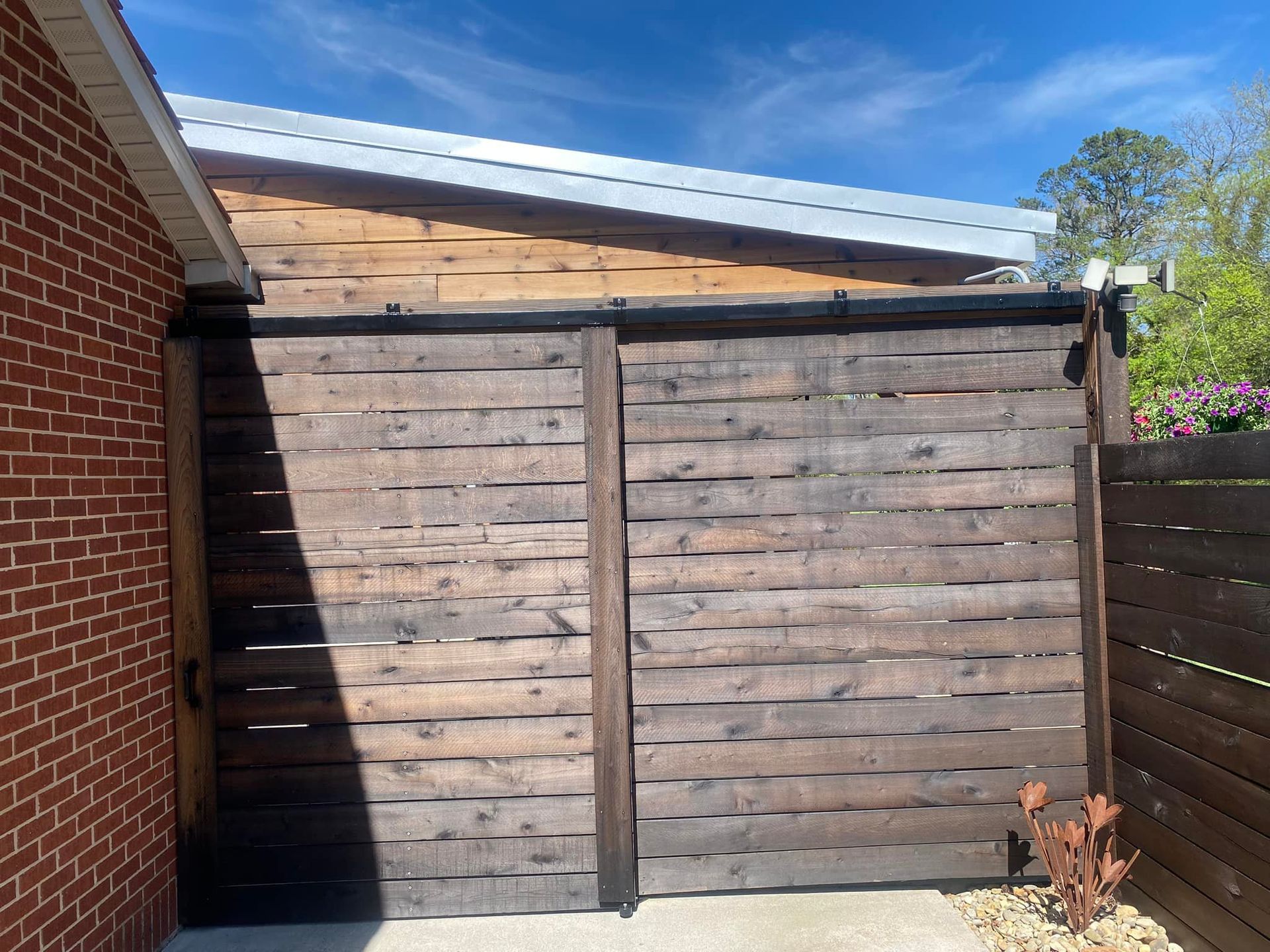 A wooden fence is sitting in front of a brick building.