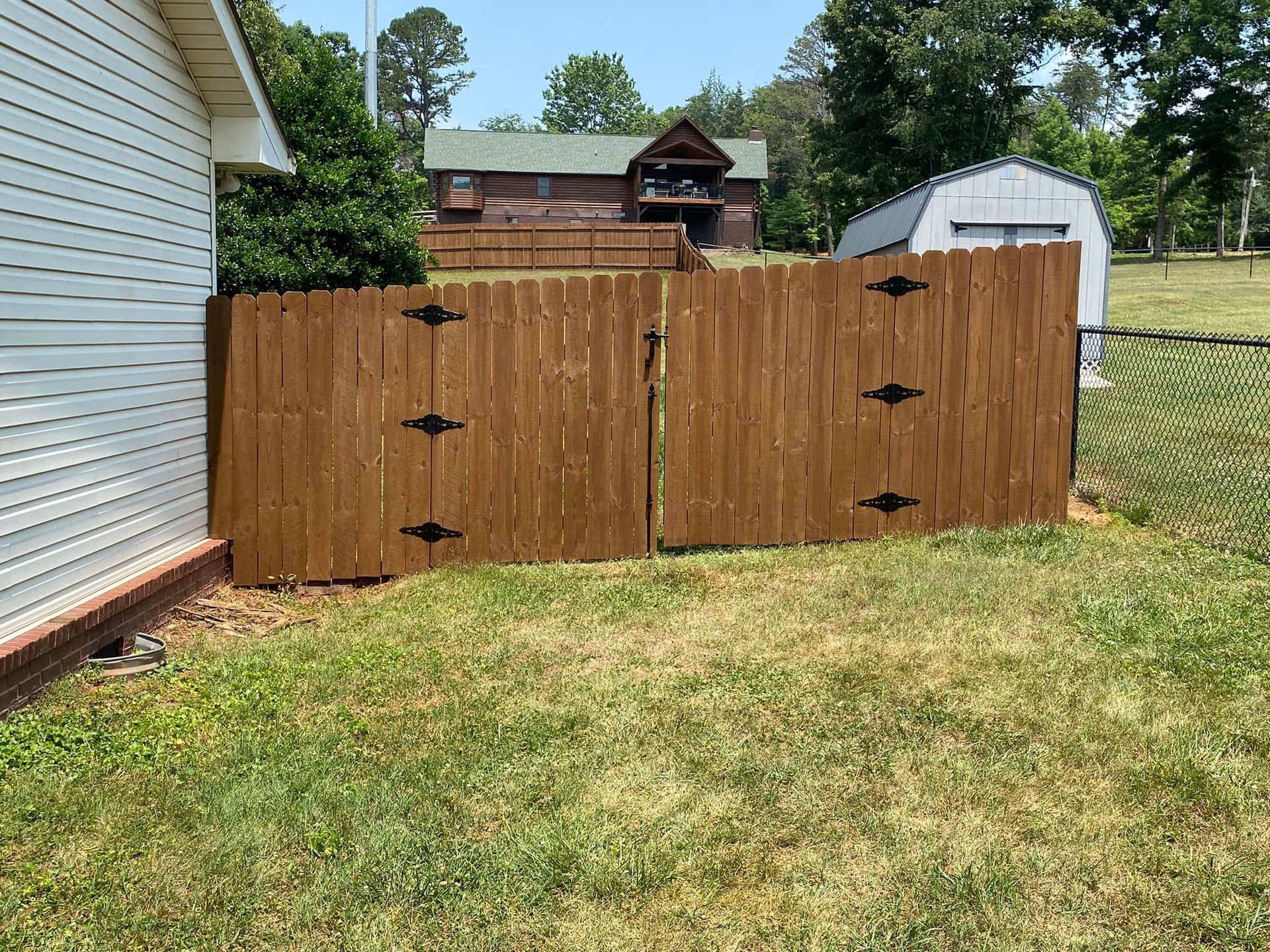A wooden fence is in the backyard of a house.