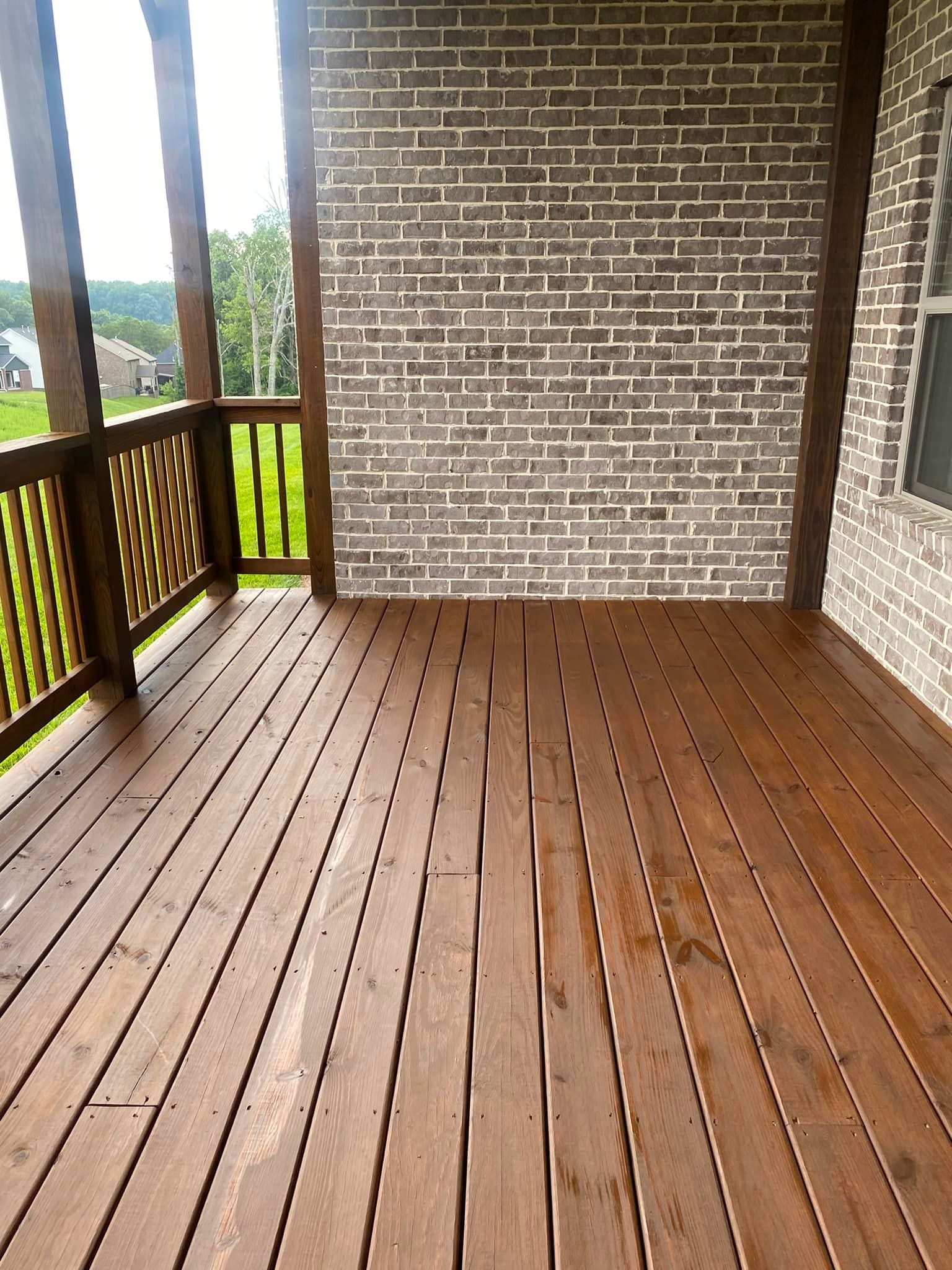 A wooden deck with a brick wall in the background.