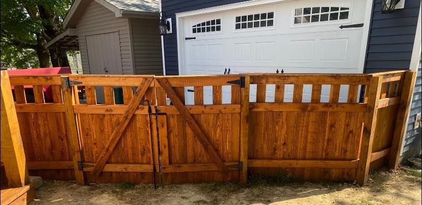 A wooden fence with a gate in front of a house.