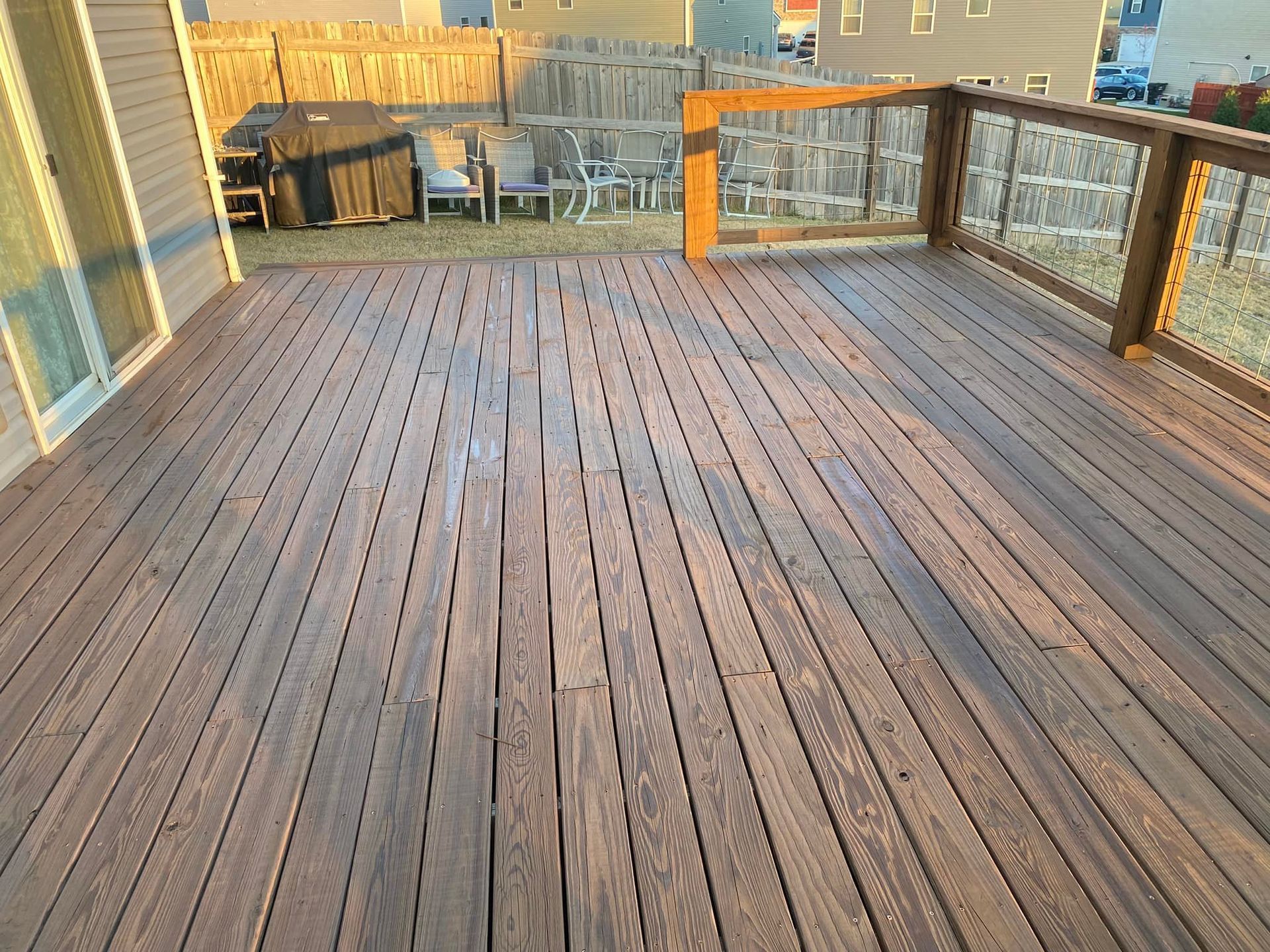 A large wooden deck with a fence and chairs on it.