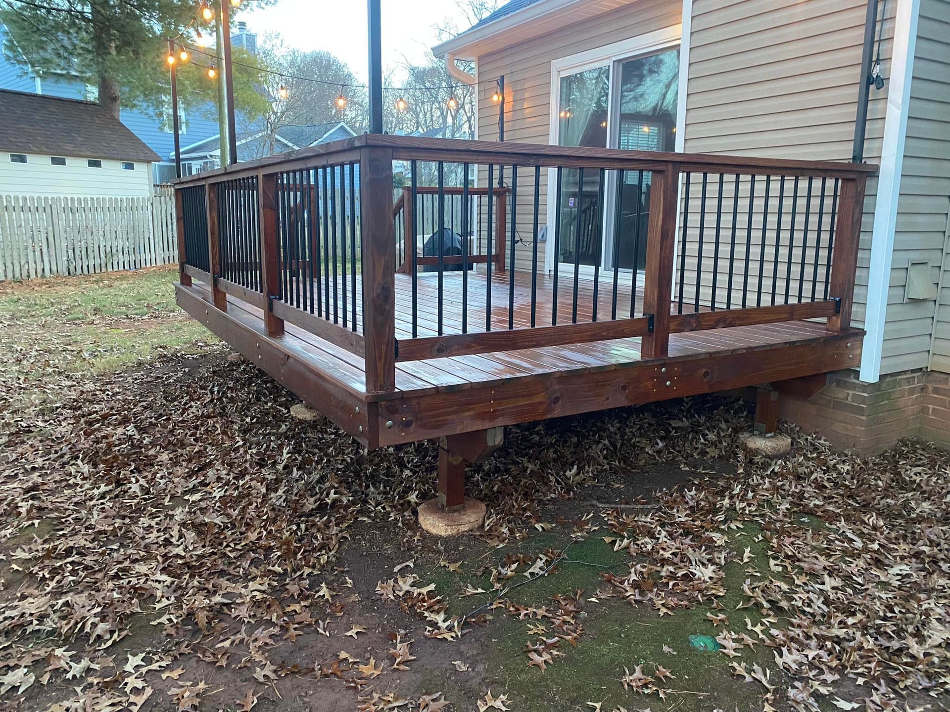 A wooden deck with a metal railing in front of a house.