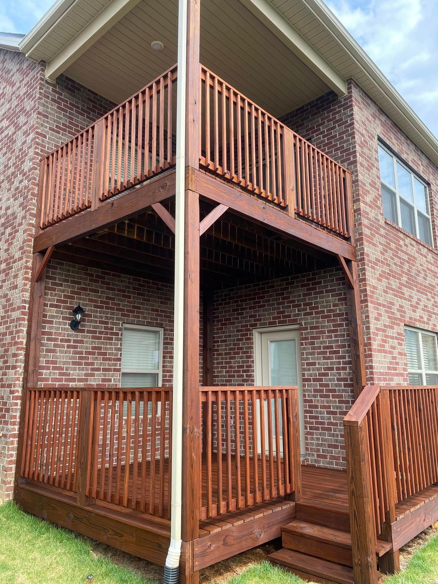 A brick house with a wooden deck in front of it.