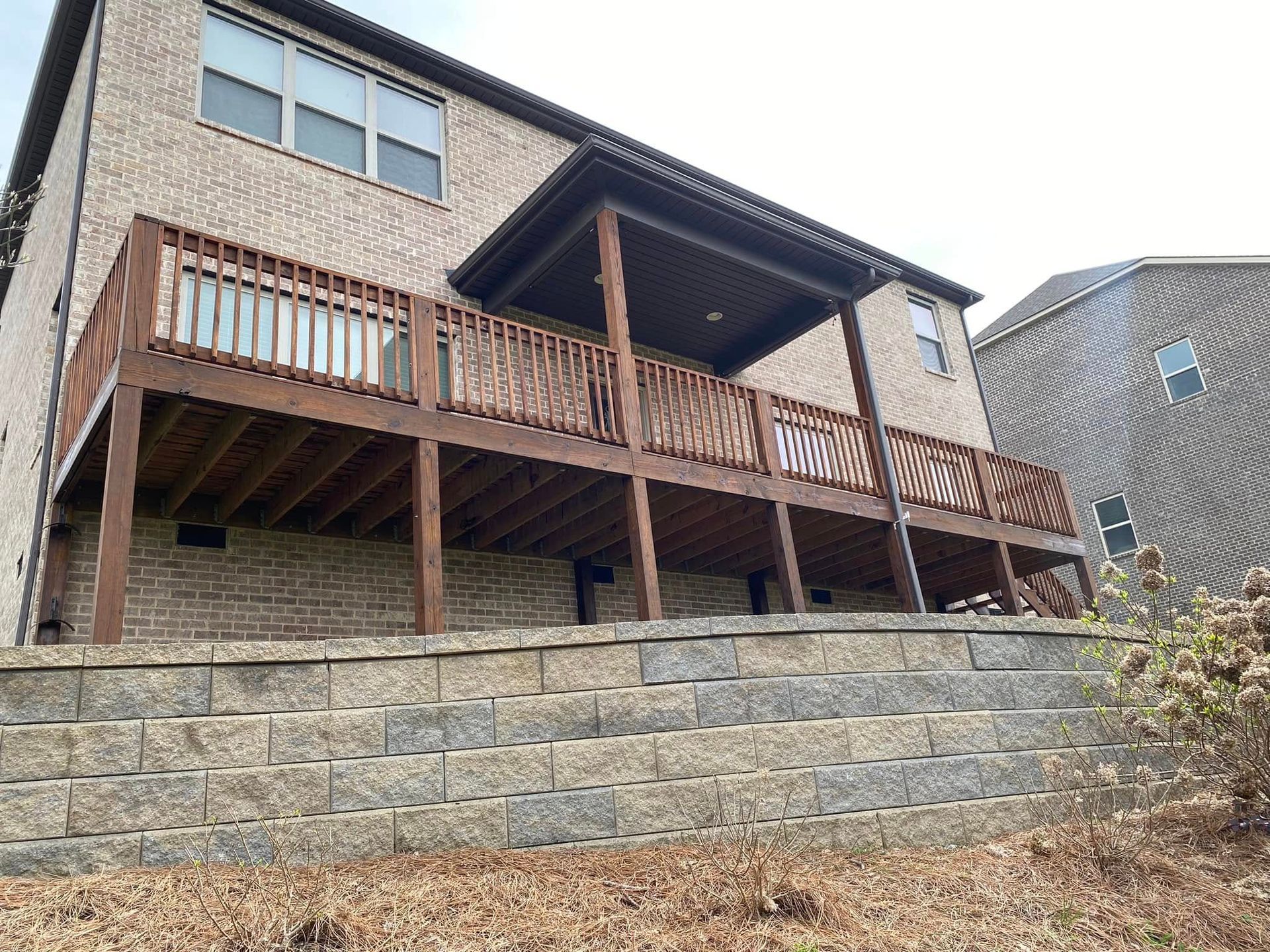 A large brick house with a wooden deck on the back of it.