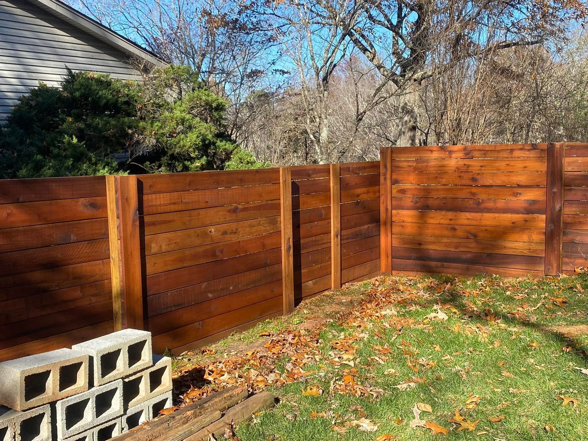 A wooden fence is in the backyard of a house.