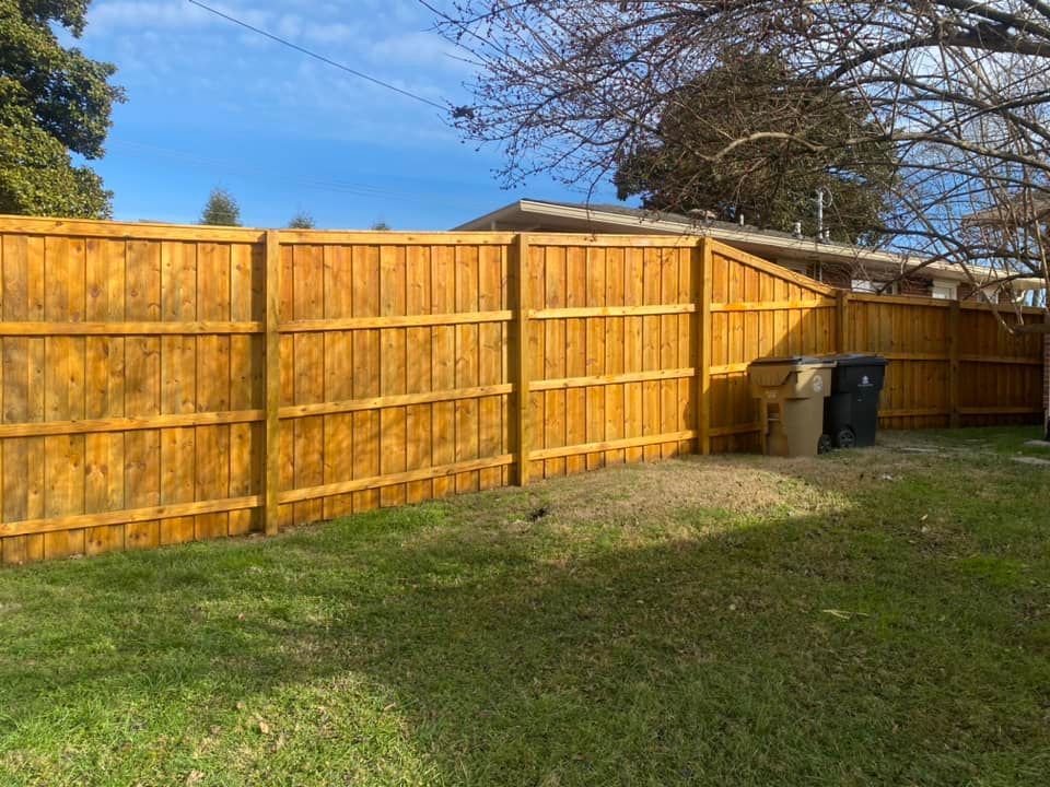 A wooden fence is in the backyard of a house.