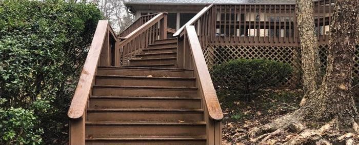 A wooden deck with stairs leading up to a house.