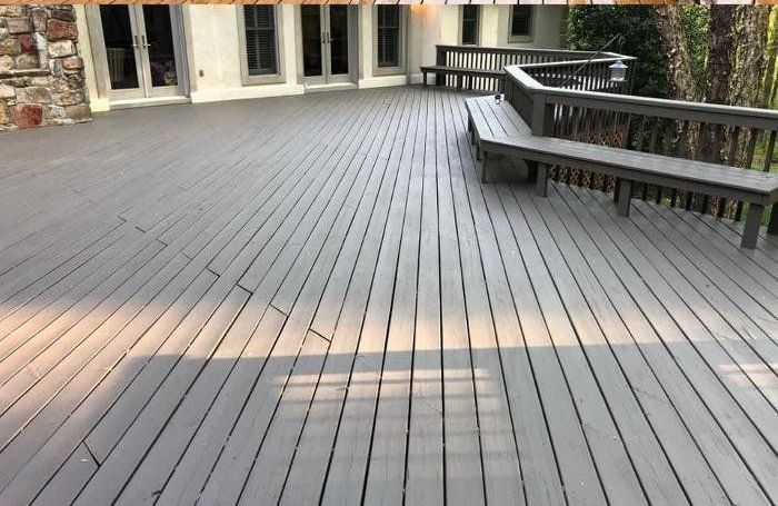 A large wooden deck with a bench on it