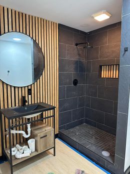 Bathroom with shower, tub, and window. Beige tile, dark shower frame, olive walls.