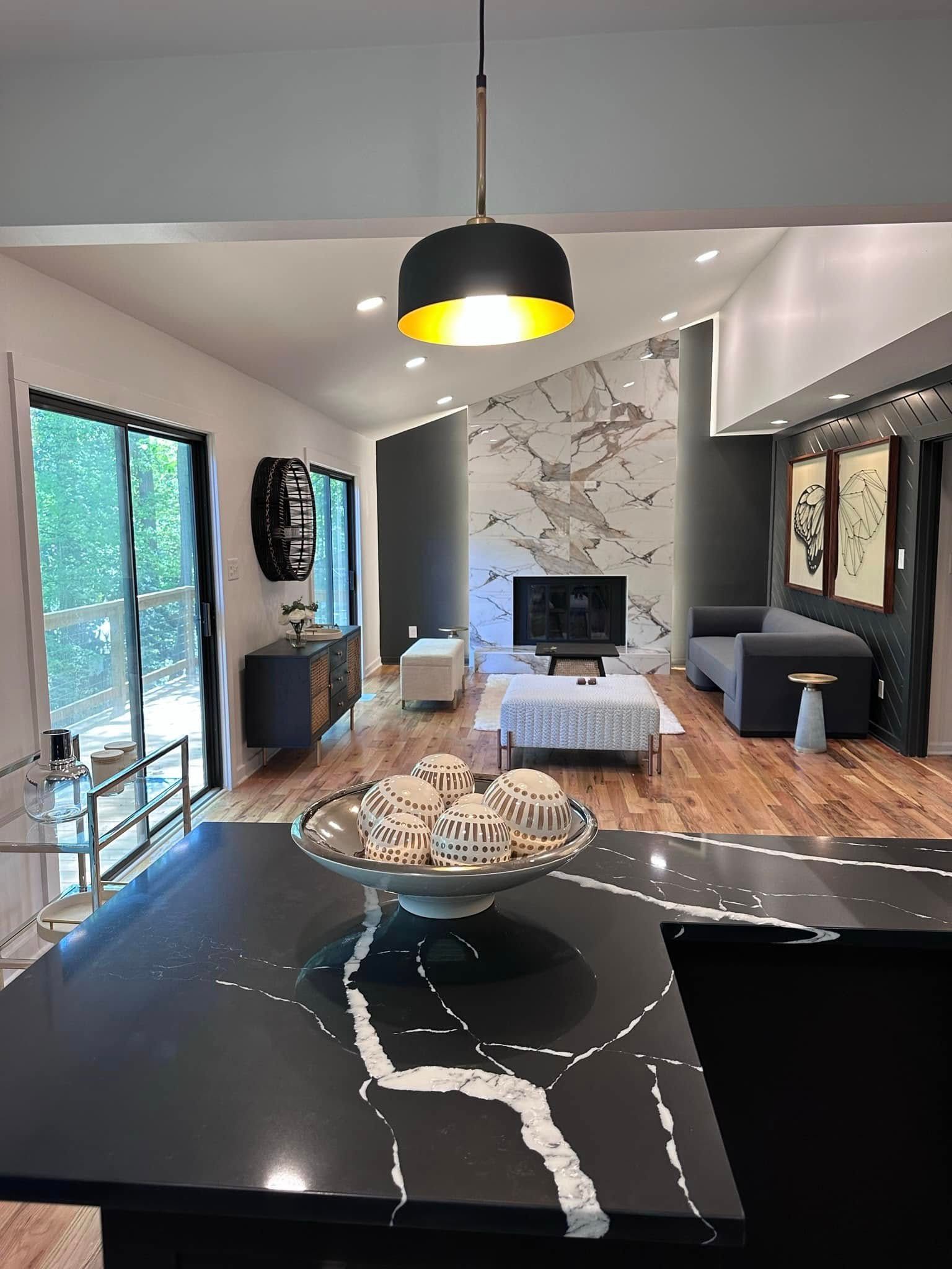 Modern living room with black and white accents. Black countertop with marble, open to the living room with fireplace.