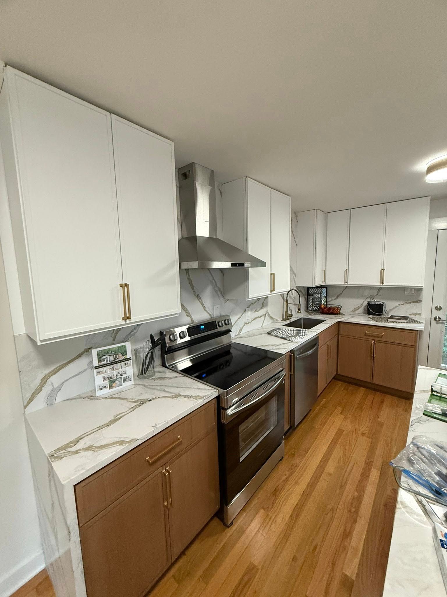 Modern kitchen with white and brown cabinets, stainless steel appliances, and marble countertops.