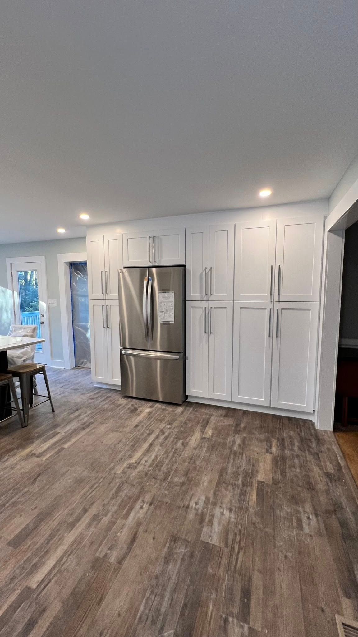 Kitchen with white cabinets, stainless steel refrigerator, and wood-look flooring.