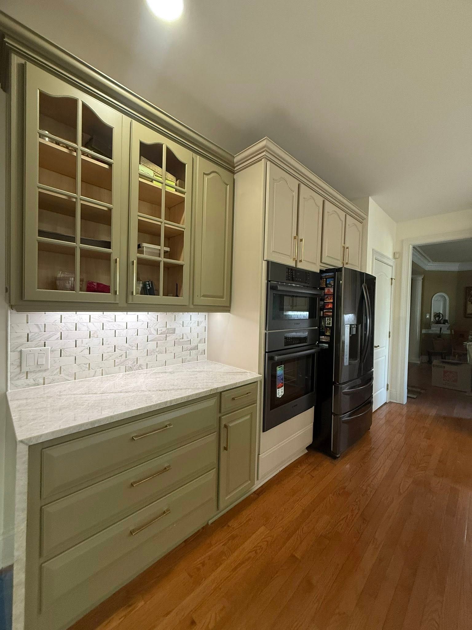 Kitchen with green cabinets, white countertops, built-in appliances, and a dark refrigerator.