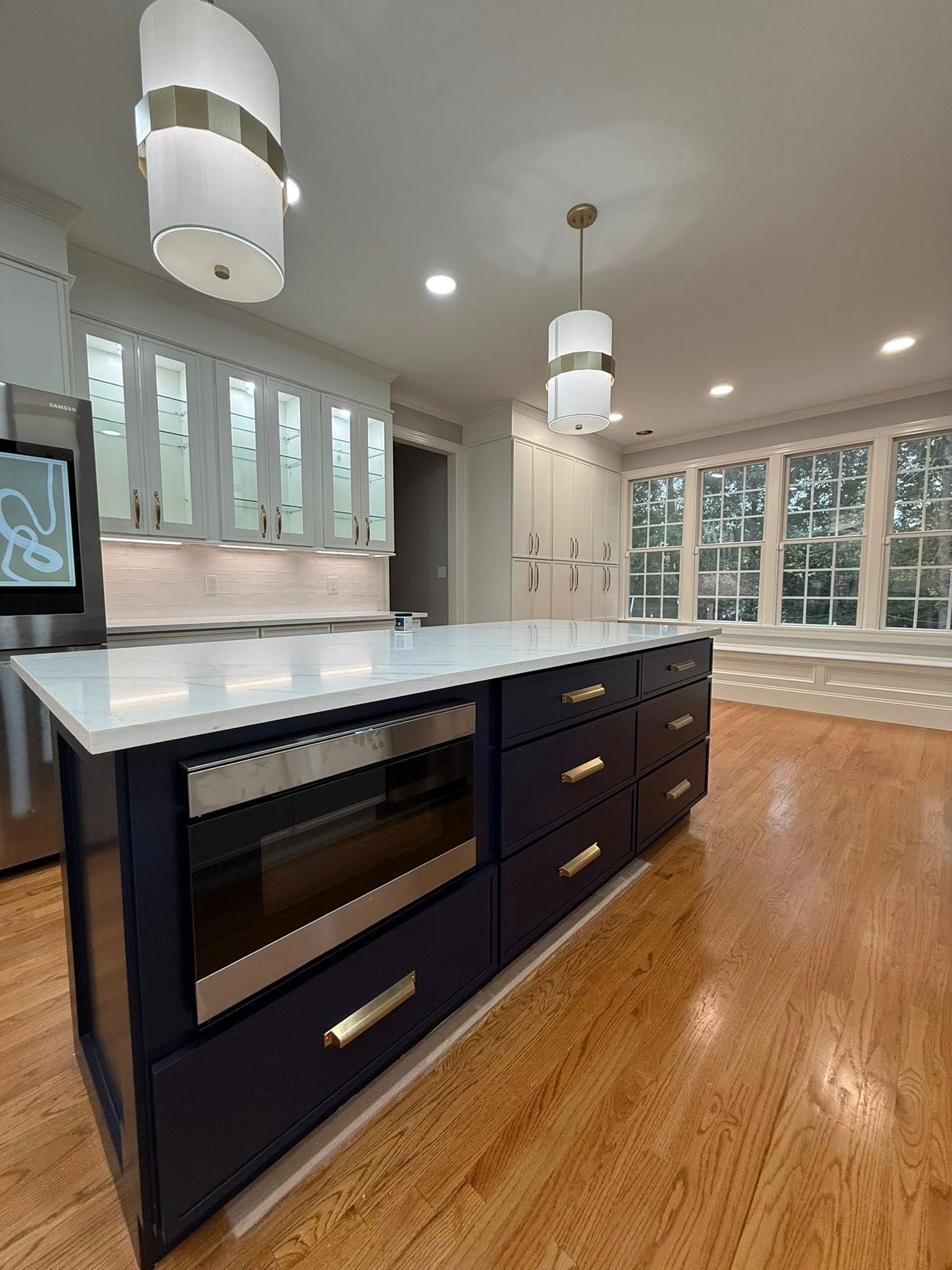 Kitchen with blue island, white countertops, stainless steel appliances, and wood floors.