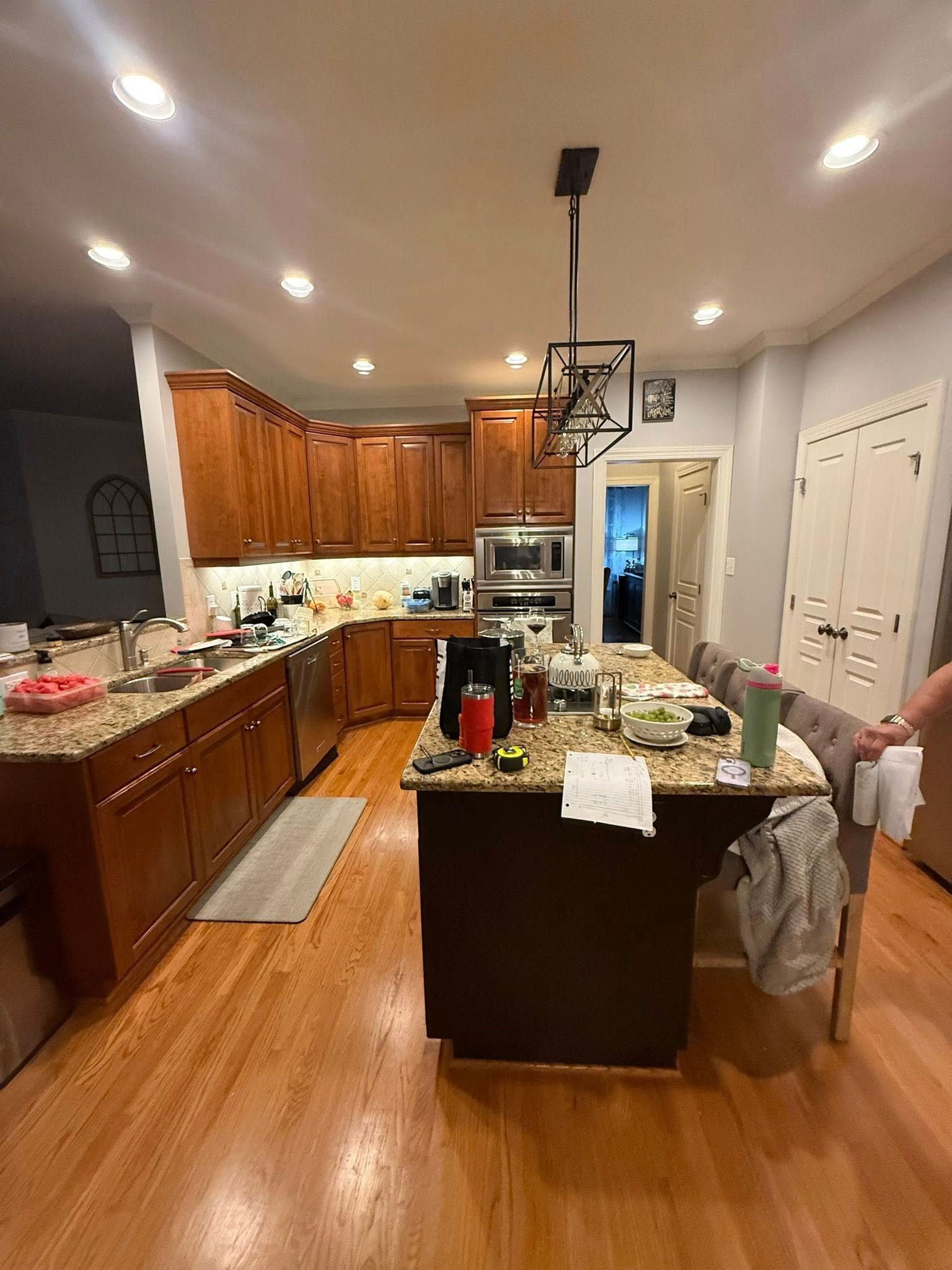 Kitchen with wood cabinets, granite countertops, and an island. A person is holding a towel.