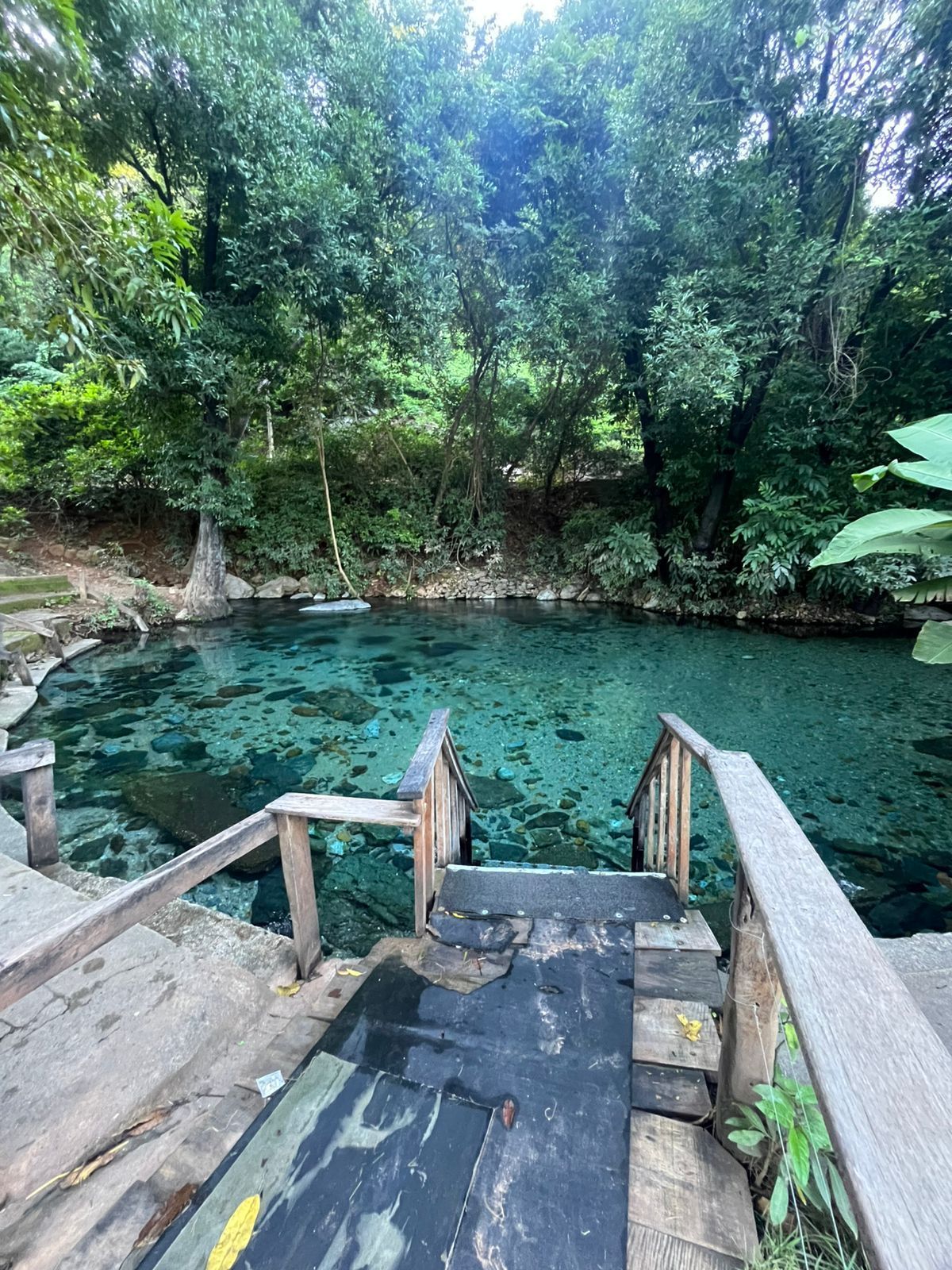 Uma escadaria de madeira leva a uma piscina natural de água cristalina turquesa