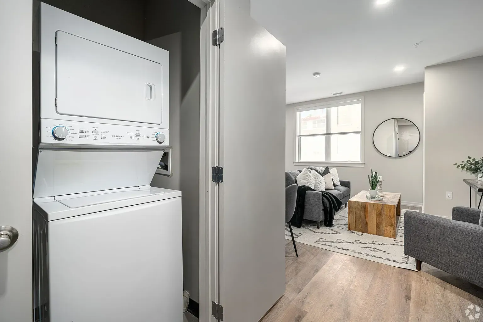 Photo of a washer and dryer closet, with the living room in the background