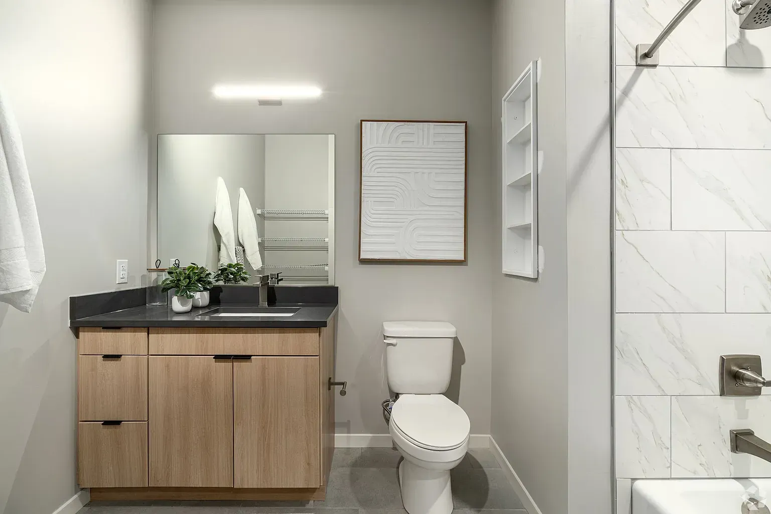 Photo of a bathroom sink and toilet with the shower/bathtub combo on the right edge of the photo