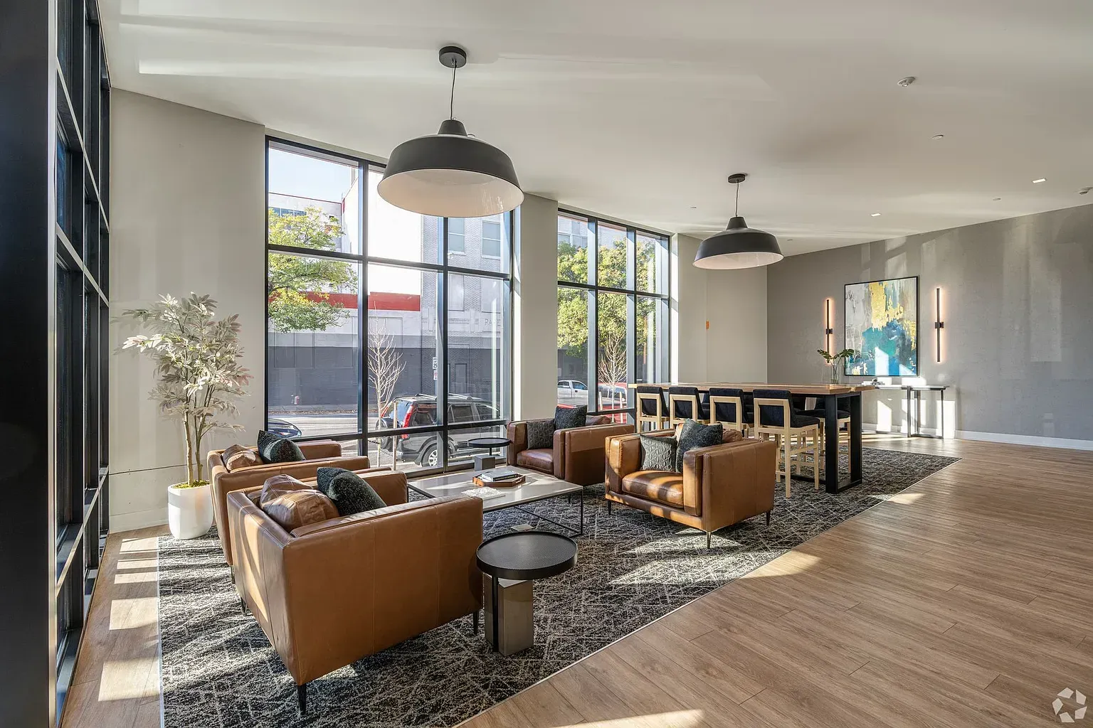 Photo of a community lounge with plenty of natural lighting, a setup of chairs surrounding a table and an island area