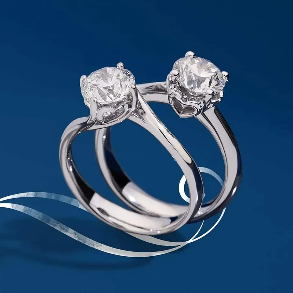 Due anelli di fidanzamento con diamanti su sfondo blu.