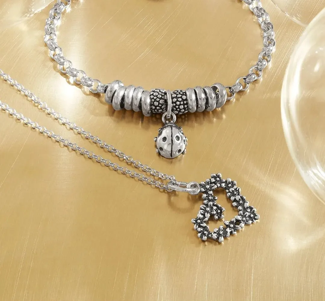 Collana e bracciale in argento con ciondoli su superficie dorata.