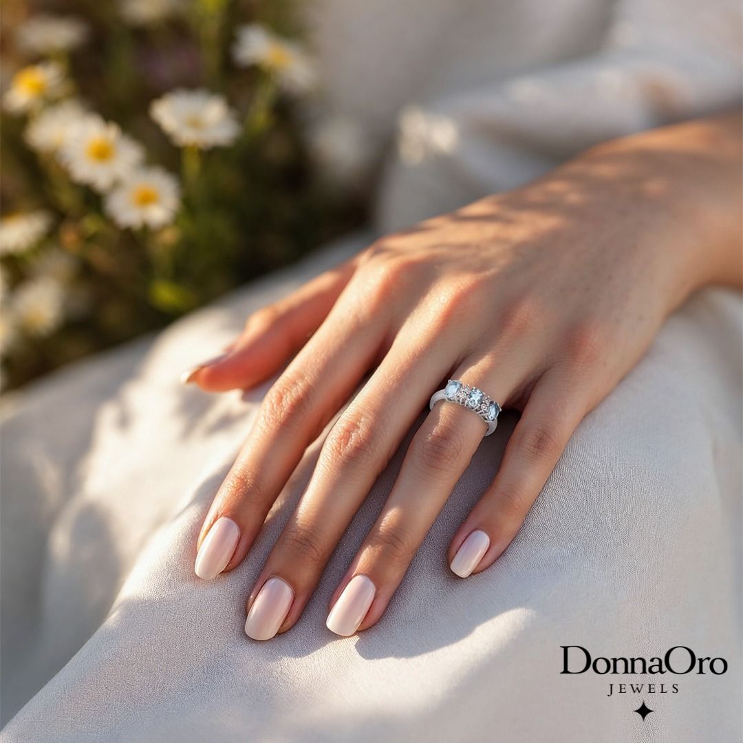 Mano che indossa un anello di diamanti su un abito bianco decorato con fiori.