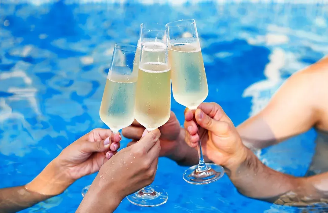 A group of people are toasting with champagne glasses in a swimming pool.