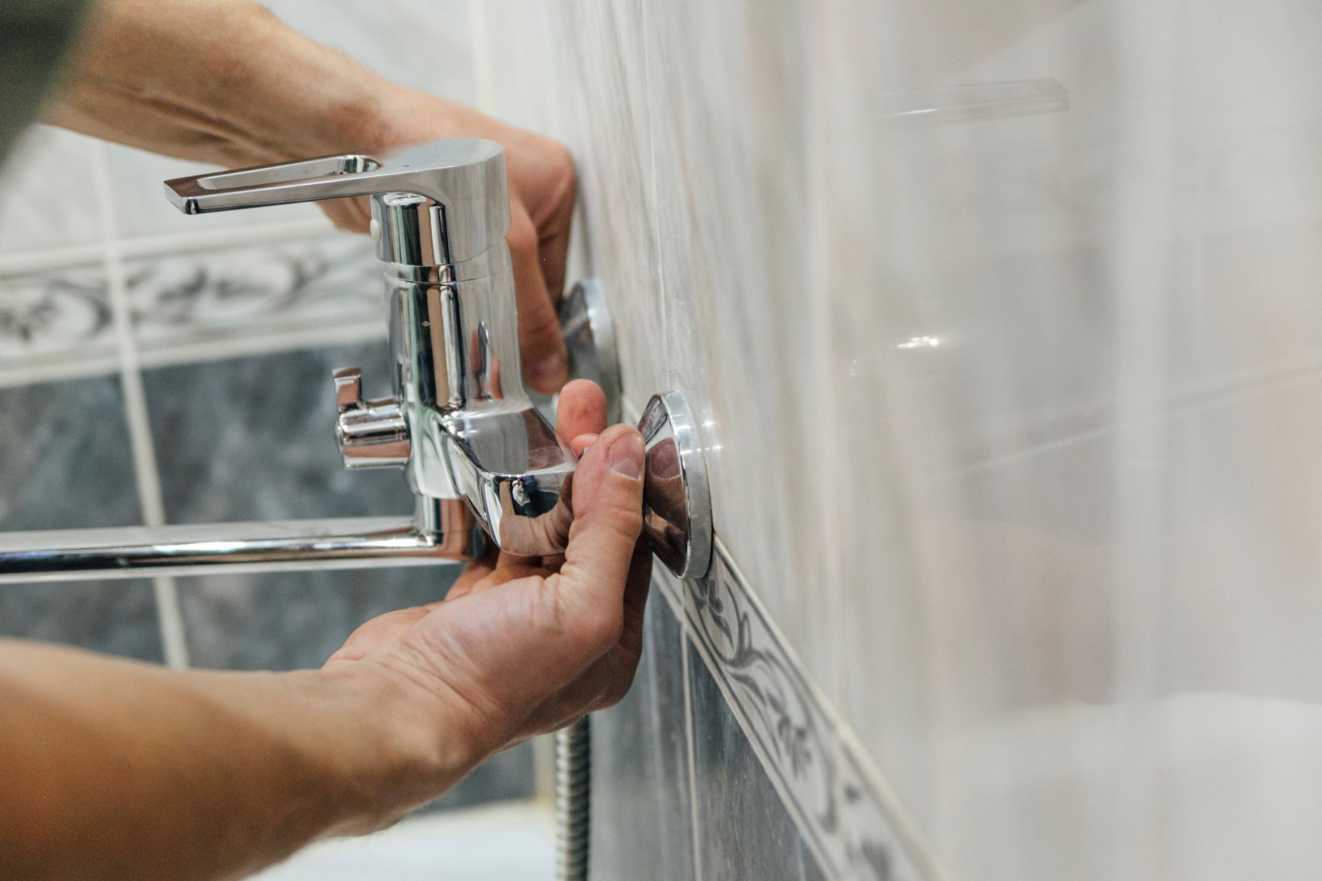 A man is fixing a shower faucet in a bathroom.