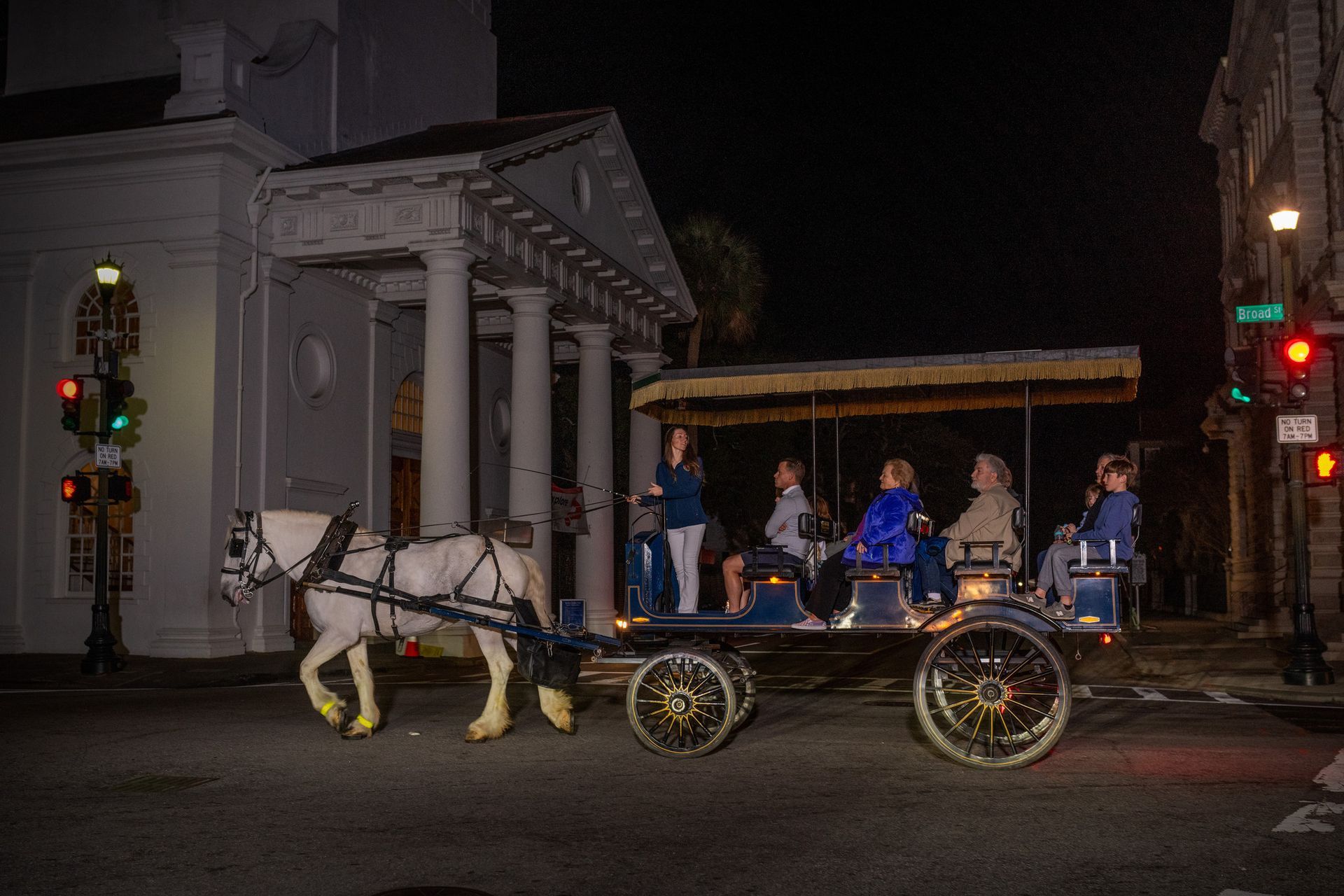 A group of people are riding in a horse drawn carriage at night.