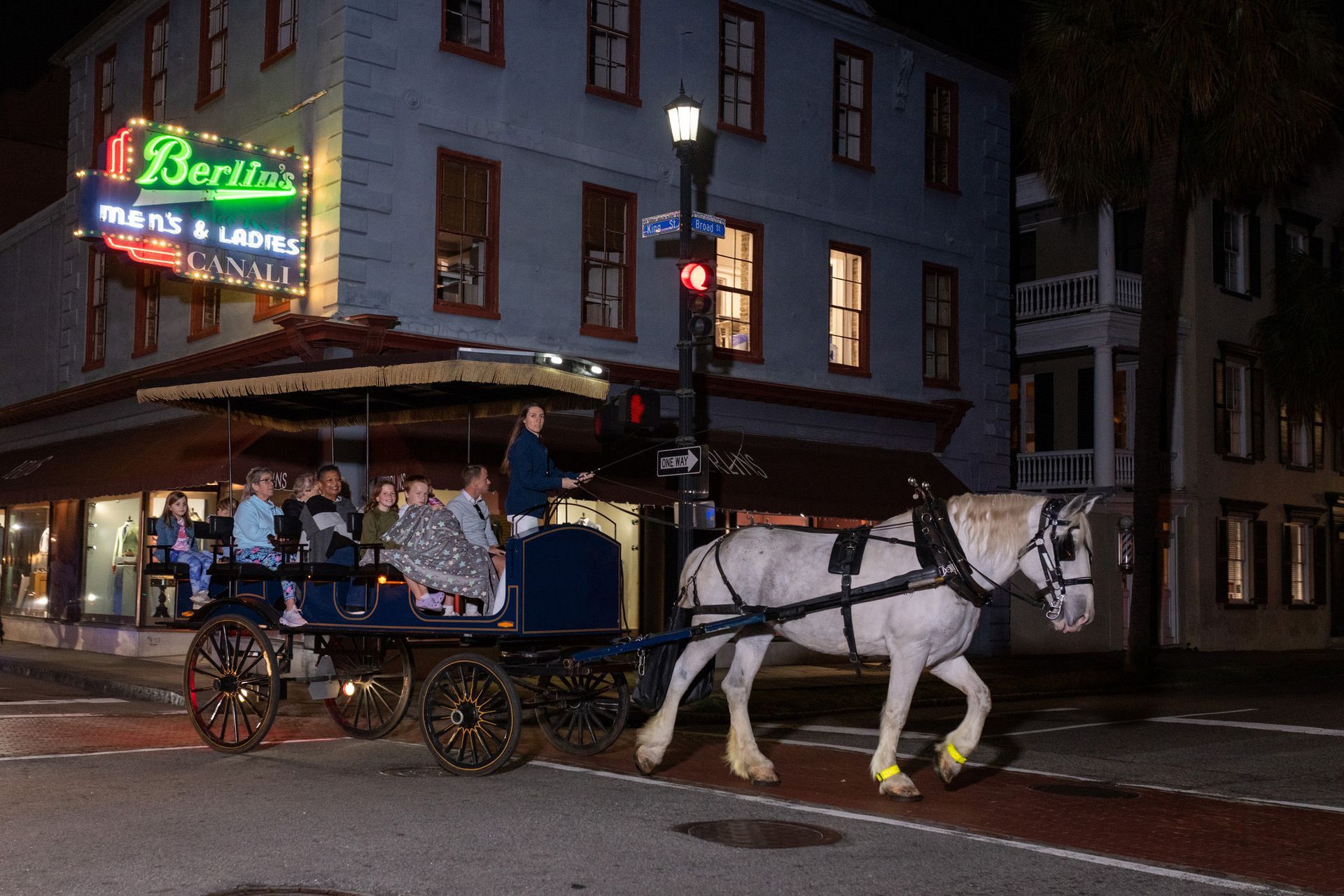 A horse drawn carriage is driving down a city street at night