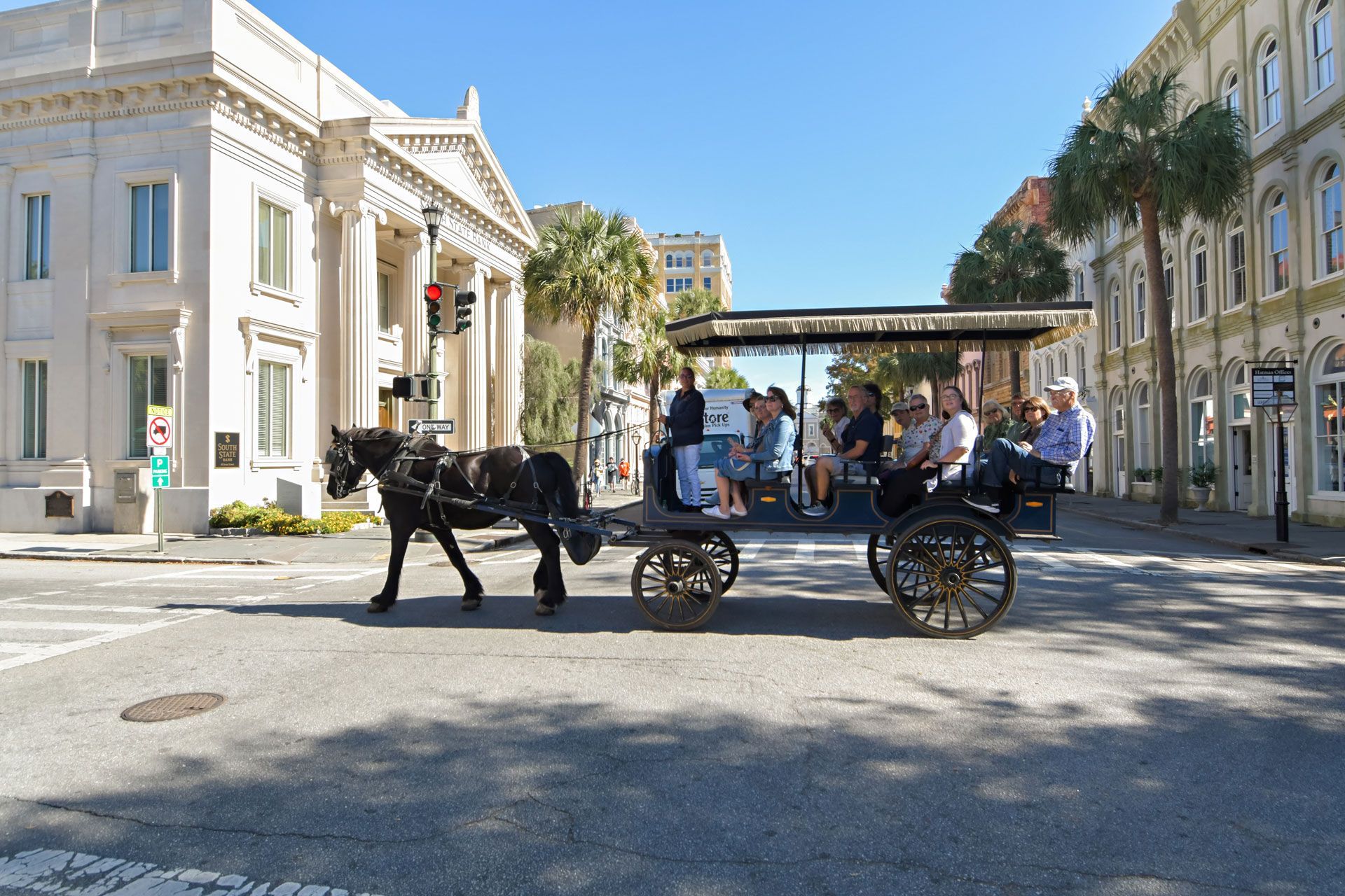 A horse drawn carriage carrying people down a city street